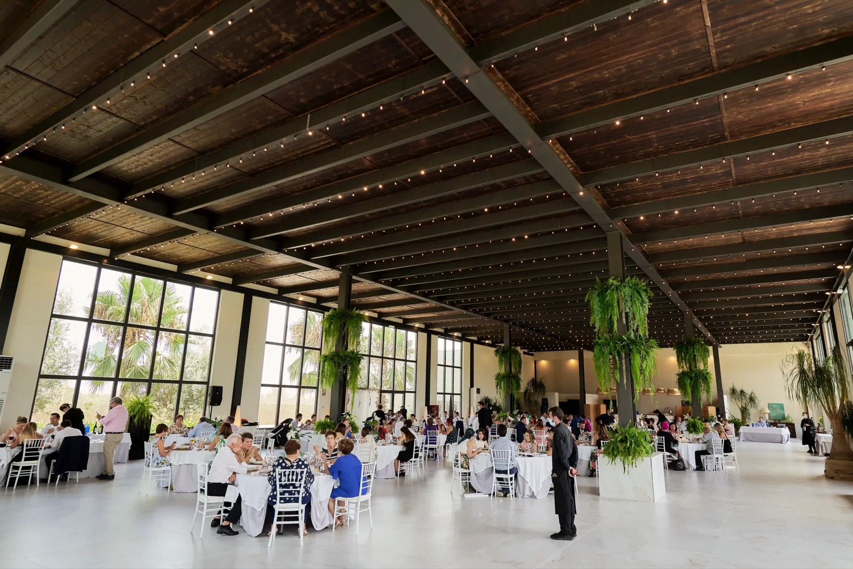 El salón del Olivo montado para el banquete, con guirnaldas de luces y grandes ventanales